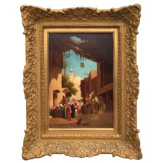 Huile sur panneau de Théodore Frère représentant une scène de rue animée au Caire, avec figures en habits traditionnels, architecture orientale et minaret à l’arrière-plan, dans un cadre en bois doré richement sculpté.